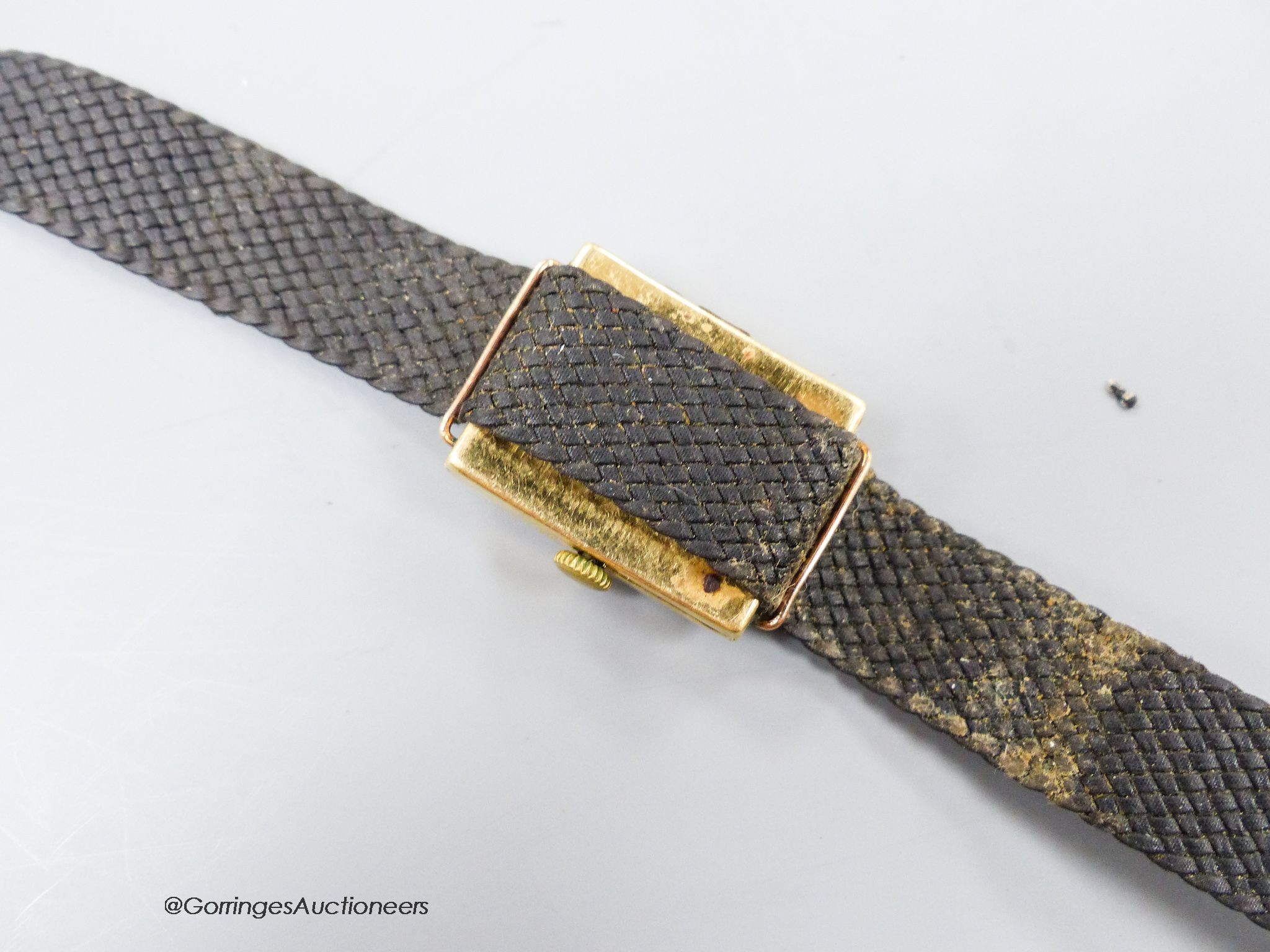 A gentleman's stylish 1920's 18ct gold Rolex manual wind curved case wrist watch, with silvered sunburst Arabic dial, case diameter 25mm, on a damaged associated fabric strap, gross weight 24 grams.